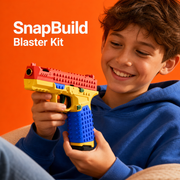 Smiling boy holding the red, yellow and blue SnapBuild brick blaster on an orange background